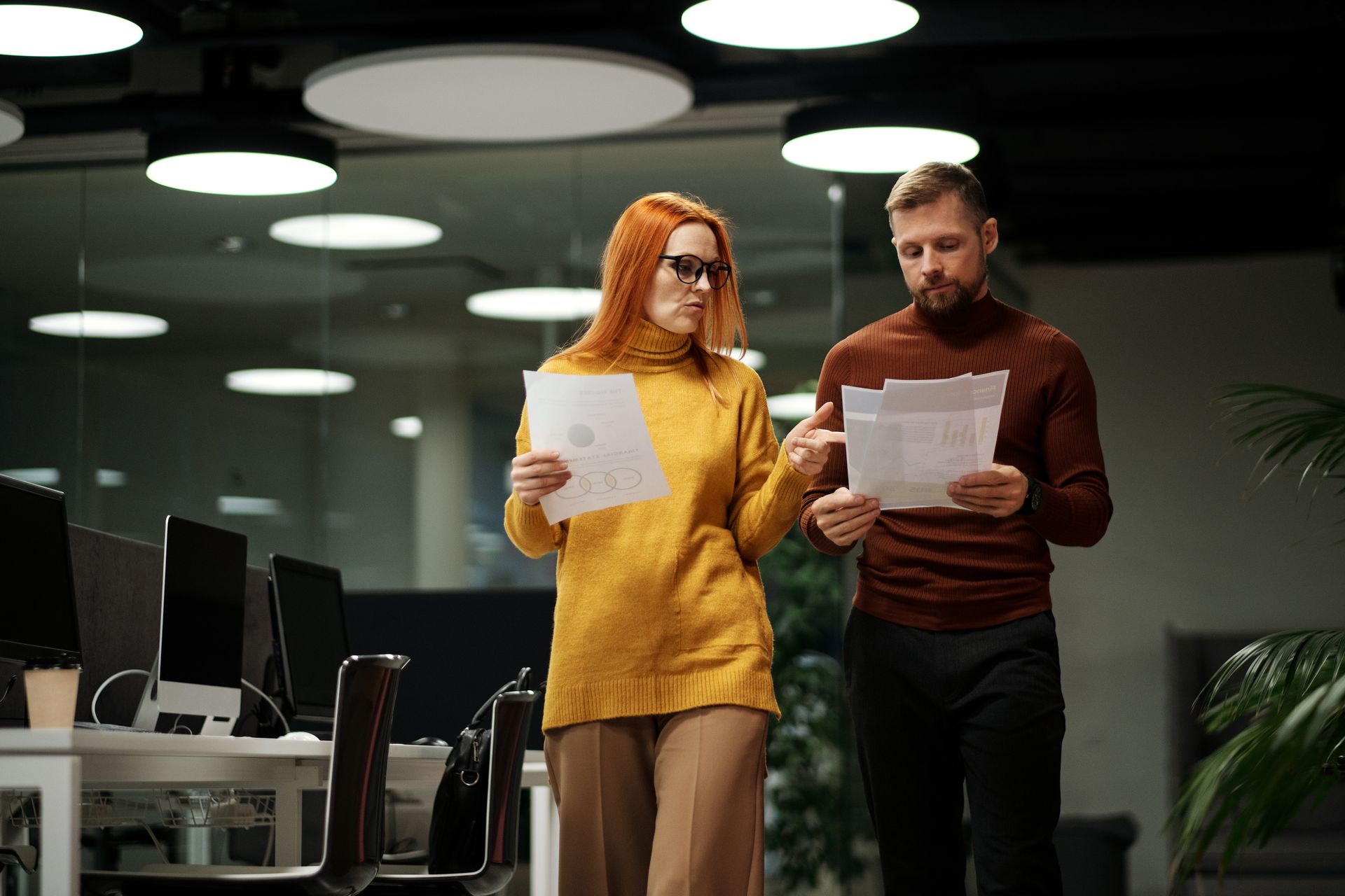 Two sales leaders walking through an office reviewing printed charts and reports during a sales team audit