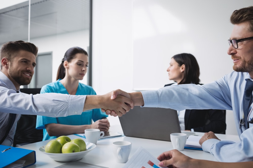 Healthcare and medical sales rep in hospital shaking hands with doctor